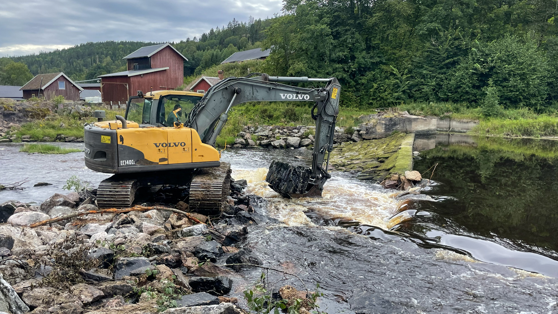 Grävmaskin som river en damm som blockerar vandringsvägar för fisk.